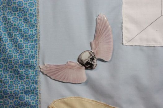 A winged skull (skull are often used in memento mori imagery) in fused glass with enamel transfers